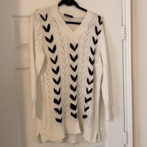 White sweater with black ribbon woven down front.
